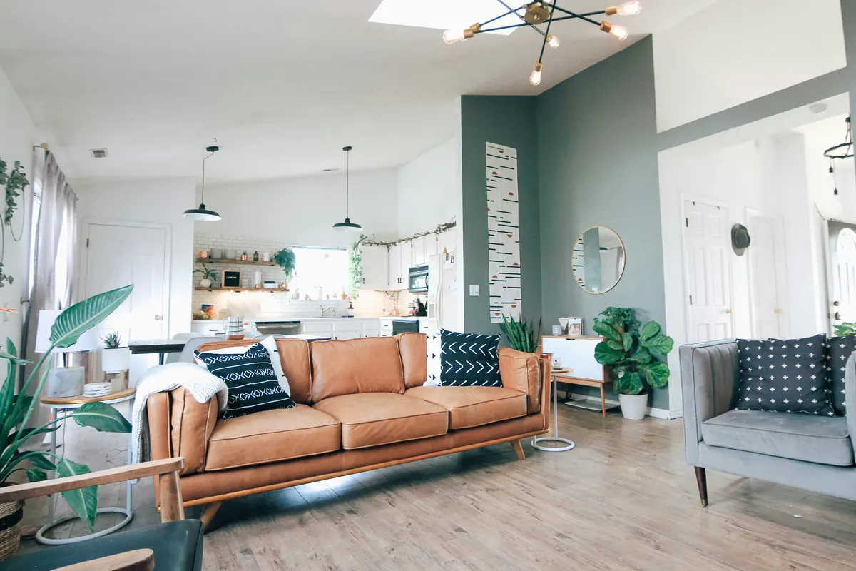 Ingerichte woonkamer met leren bank, kamerplanten en een open keuken op de achtergrond