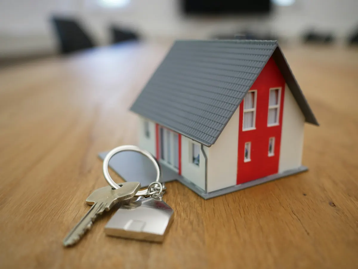 Huissleutel met een miniatuurhuisje als sleutelhanger op een houten tafel