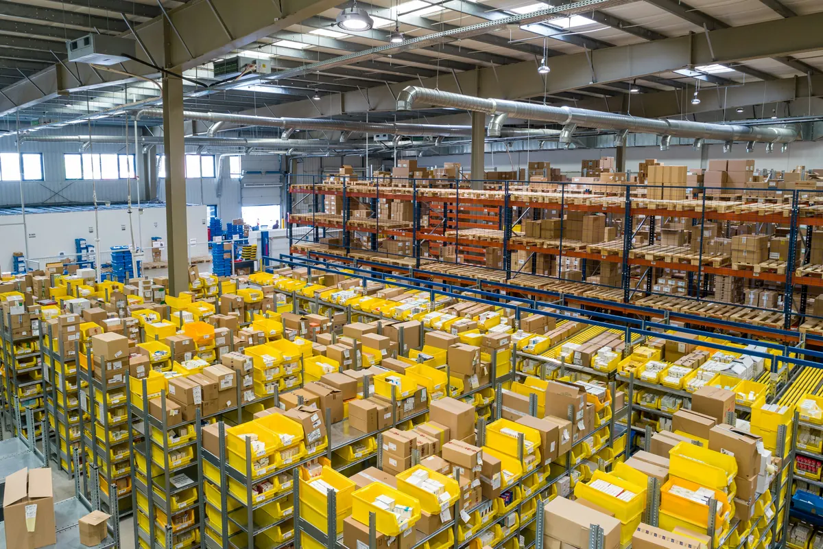 Magazijn met stellingen vol kartonnen dozen en gele kratten